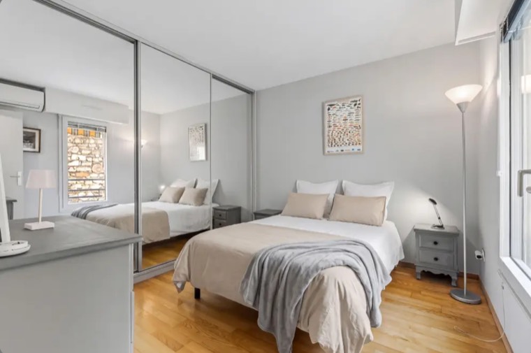 The same bedroom with the bed styled, and the change carried correctly into the mirror