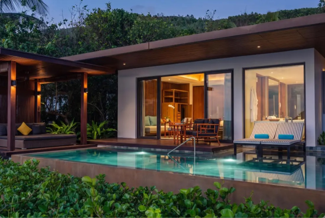 Resort villa and private pool at dusk, interior lights on